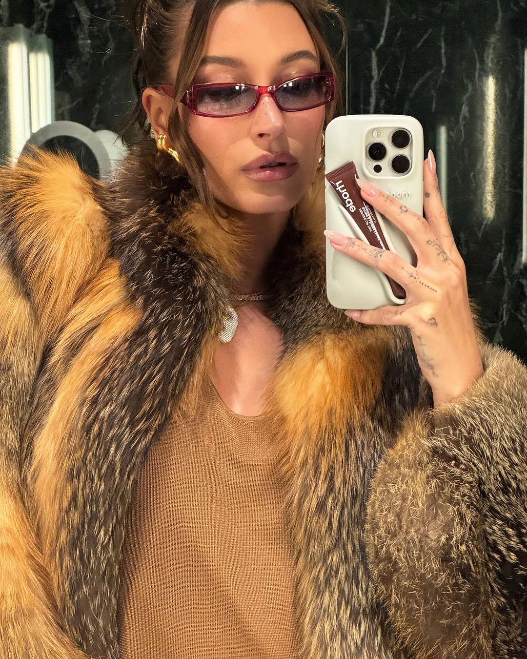 hailey bieber taking picture in mirror while wearing sunglasses